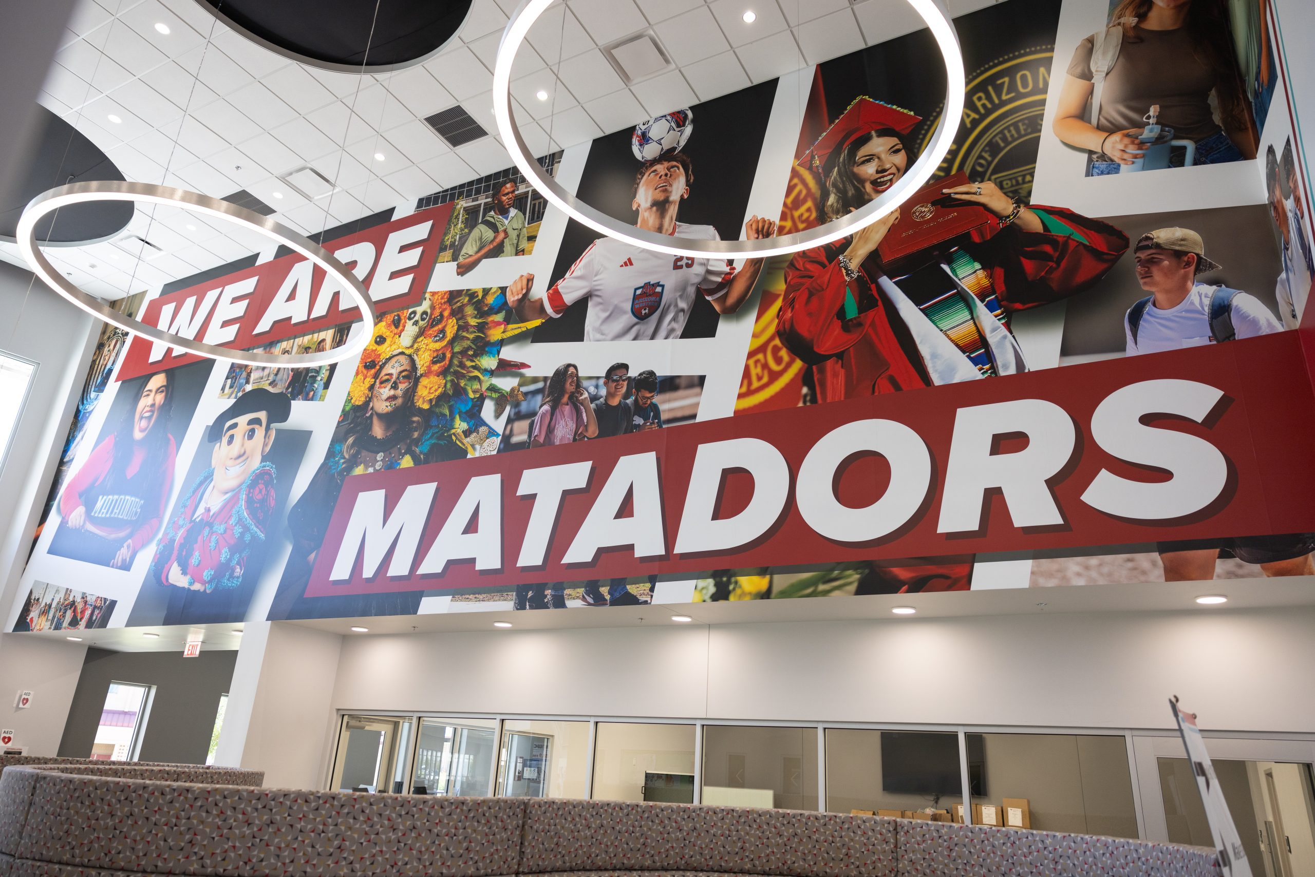 A vibrant mural featuring diverse students and athletes with the bold text "WE ARE MATADORS" hangs prominently in a modern indoor space.