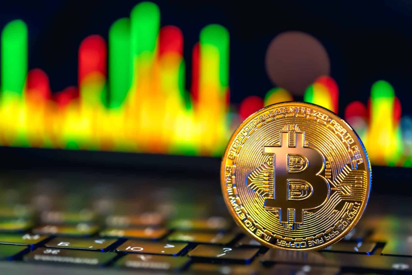 金色比特幣放在鍵盤上，背景為K線走勢圖的示意圖